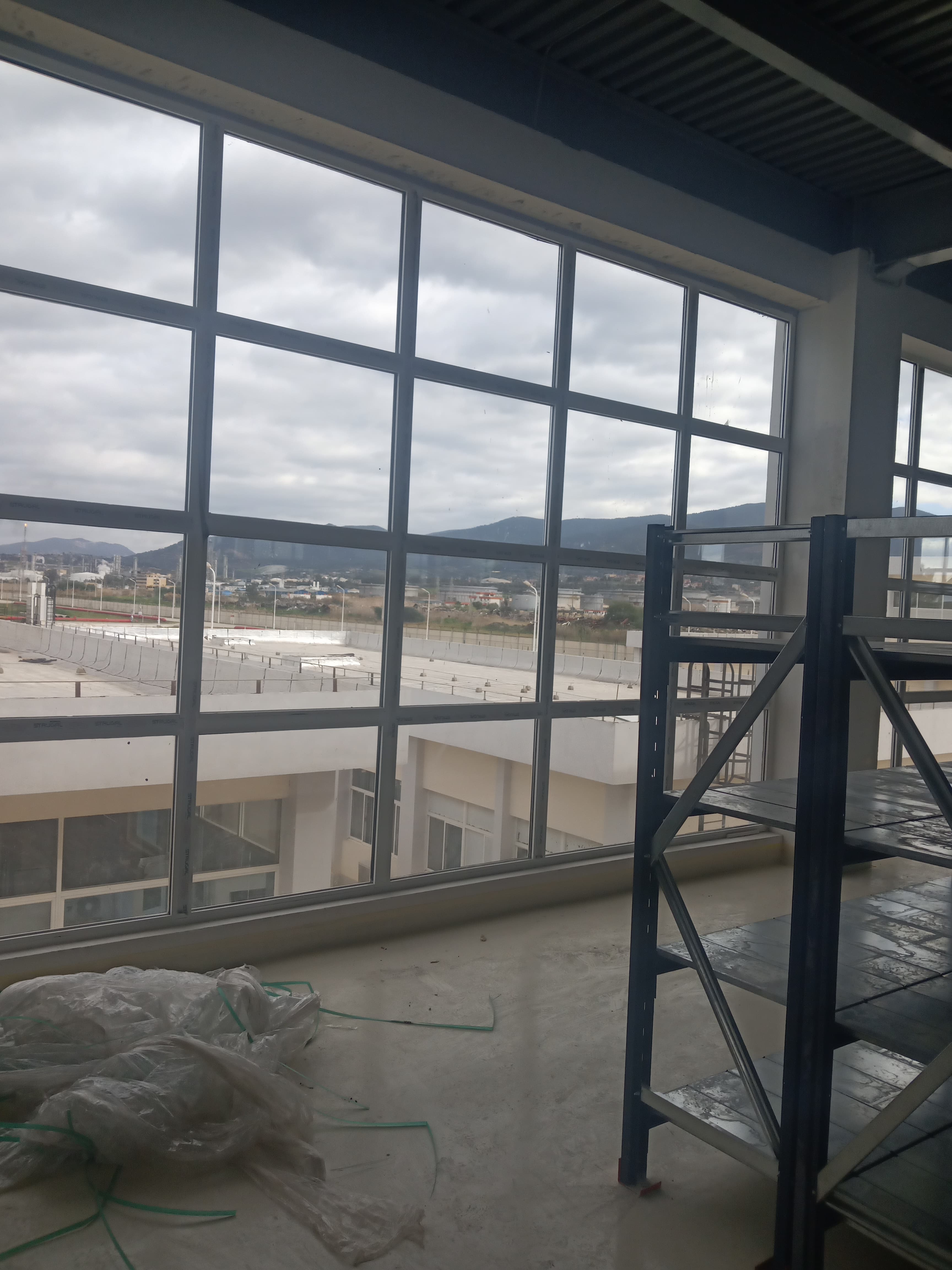 Grande baie vitrée aluminium à vitrages fixes multiples ouverte sur un panorama de collines